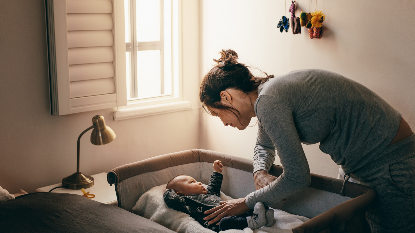 Mother tending to baby in crib