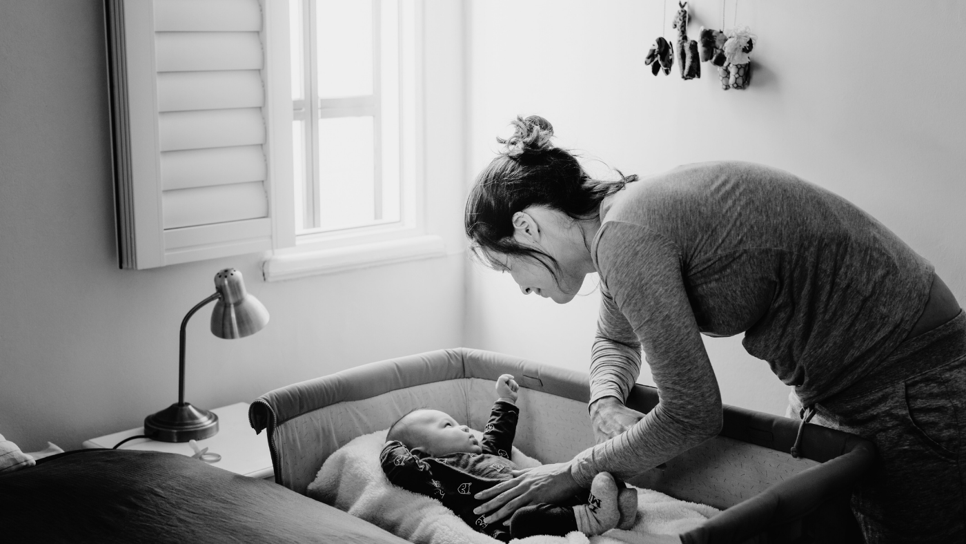 Mother tending to baby in crib